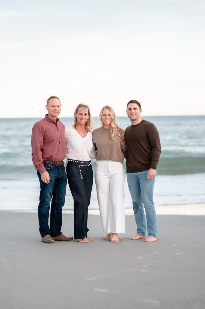 Parents smiling proudly during their daughter’s Jacksonville Beach proposal celebration.