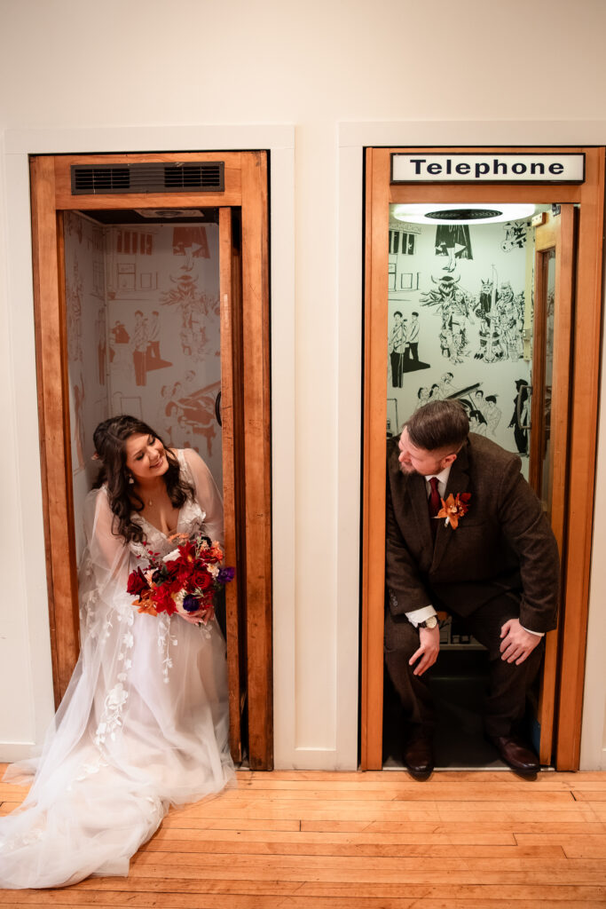 Couple posing playfully inside vintage phone booths at Common House Richmond wedding venue.