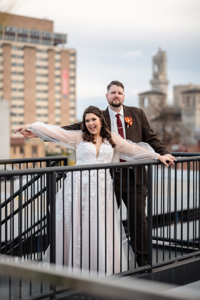 Bride and groom holding hands on a rooftop balcony during fall wedding portraits in Richmond Virginia.
