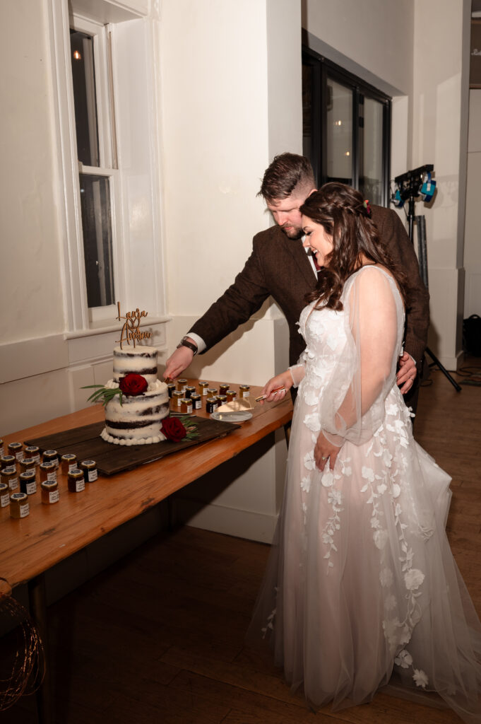 Bride and groom laughing during a playful cake cutting moment.