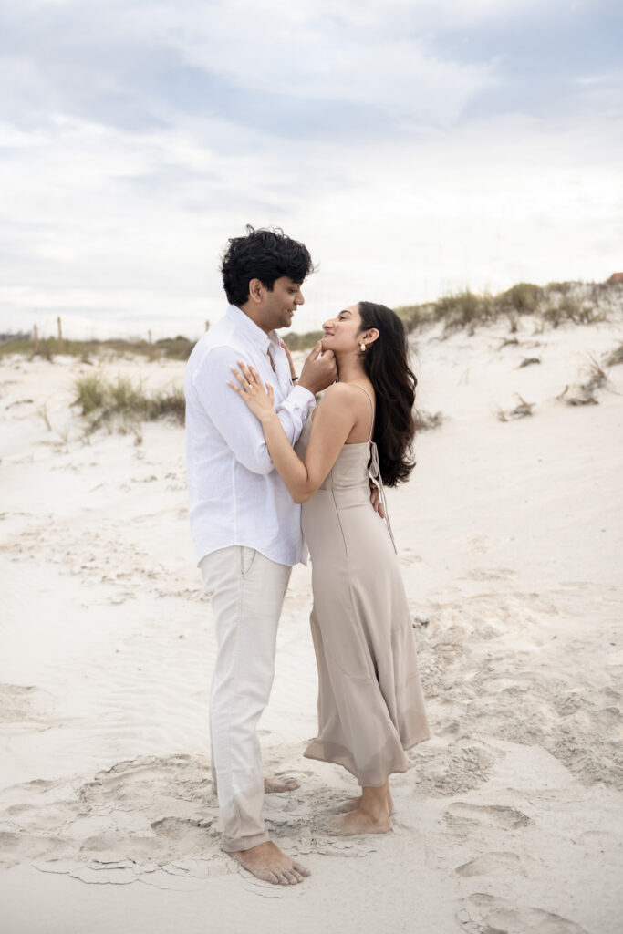 Newly engaged couple showing off engagement ring on the beach.