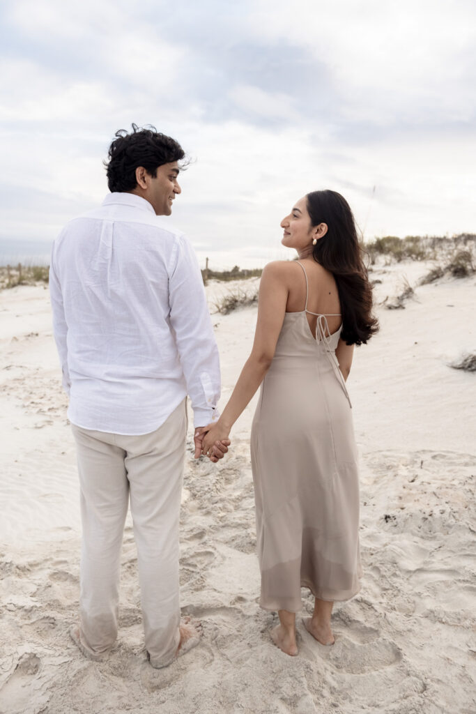 Couple walking barefoot along Crescent Beach after getting engaged.